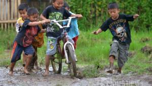 Sejumlah-anak-bermain-sepeda-di-atas-lumpur-akibat-tergenang-air-hujan.jpg