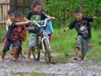 Sejumlah-anak-bermain-sepeda-di-atas-lumpur-akibat-tergenang-air-hujan.jpg