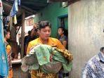 warga-menggendong-bayi-berusia-satu-bulan-yang-tewas-di-dalam-rumahnya-1.jpg