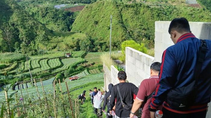 WISATA TRACKING GUCI - Peserta tracking sedang menyusuri area persawahan dekat permukiman dengan pemandangan di kawasan wisata Guci, Kabupaten Tegal, Jawa Tengah, Jumat (7/11/2025). Tracking di perbukitan menjadi wisata baru di Guci selain pemandian air hangat.
