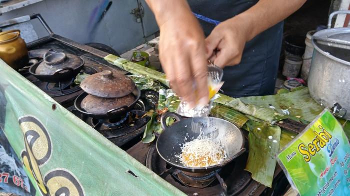 JAJANAN SERABI - Denis, penjual serabi khas Banyumas memeri toping saat melayani pembeli di kedai serabi Banyumas Jalan Gatot Subroto atau di seberang Pasar Manis Purwokerto, Kabupaten Banyumas, Selasa (10/2/2026). Harga serabi Banyumas itu dijual mulai Rp2.000 per buah.