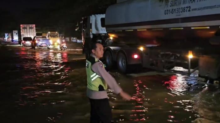 BANJIR - Anggota Polsek Batangan Bripka Arif Widya memantau kondisi Jalan Pantura di wilayah Desa Ketitang Wetan, Kecamatan Batangan, Kabupaten Pati, yang kebanjiran akibat limpasan air sungai setempat, Rabu (10/12/2025).