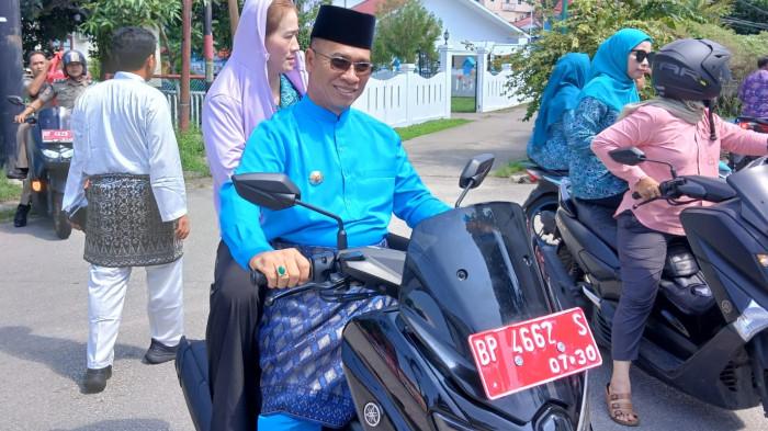 BUPATI ANAMBAS - Bupati Kepulauan Anambas, Aneng membonceng istri, Sinta menyusuri jalan di Tarempa, ibu kota Kabupaten Kepulauanb Anambas baru-baru ini. Bupati Kepulauan Anambas, Aneng, menjadi sorotan masyarakat setelah menolak pengadaan mobil dinas baru senilai Rp 1,5 miliar yang sebelumnya direncanakan oleh pemerintah daerah.