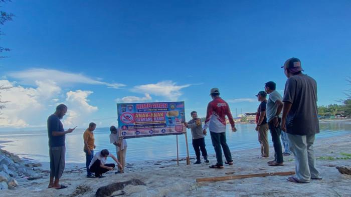 PANTAI PIWANG NATUNA - Bhayangkara Pembinan Keamanan dan Ketertiban Masyarakat (Bhabinkamtibmas) bersama Bhabinsa, aparatur kelurahan, dan warga Kelurahan Baru Hitam, saat memmasangan spanduk peringatan di pesisir Pantai Piwang,  Kabupaten Natuna, Provinsi Kepulauan Riau (Kepri), Minggu (24/5/2026).