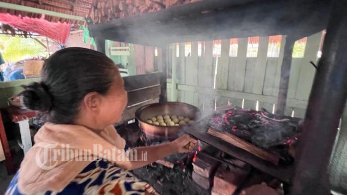 PANGGANG ROTI - Maryam alias Nek Yam (72), saat sedang mengatur bara api untuk memanggang roti secara tradisional di dapurnya berlokasi di Kampung Gelam, Daik Lingga, Kepulauan Riau, Kamis (16/4/2026).