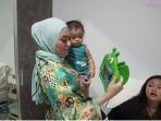 Nathalie-Holscher-yang-memegang-Tablet-dan-menggendong-Adzam-Adrriansyah-Sutisna.jpg