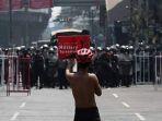 seorang-pengunjuk-rasa-mengusung-poster-di-hadapan-barisan-polisi-myanmar.jpg