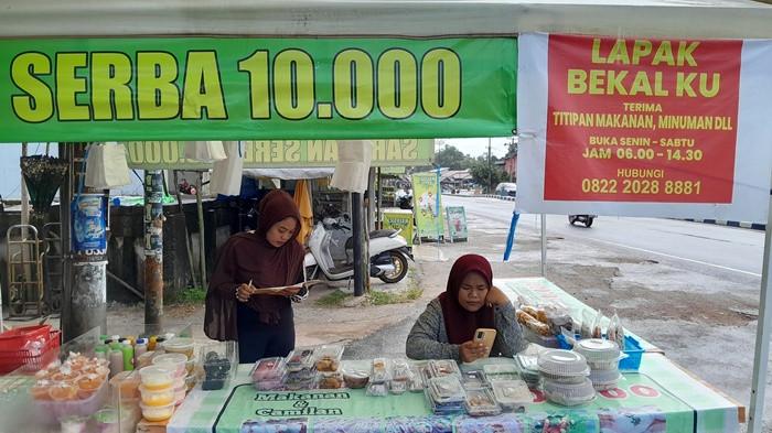 SERBA SEPULUH RIBU - Pekerja di Lapak Bekalku bersiaga di bawah tenda gazebo putih di pinggir Jalan Jenderal Sudirman, Perawas, Tanjungpandan, Rabu (18/2/2026). Gerai yang menawarkan konsep harga serba sepuluh ribu ini menjadi pilihan favorit pengendara dan warga sekitar untuk mendapatkan jajanan praktis, terutama di pagi hari sebelum beraktivitas.