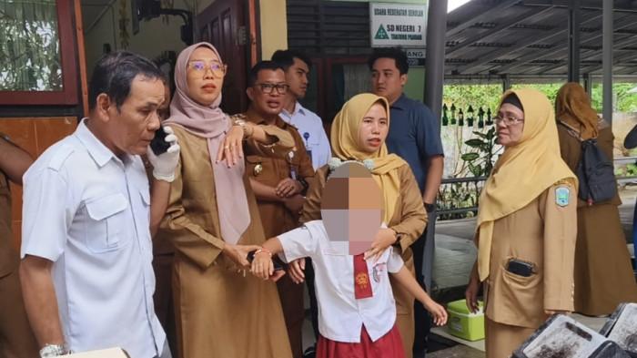 MEMAPAH MURID -- Kepala SD Negeri 7 Tanjungpandan, Asti Ramdaniati memapah muridnya yang akan dibawa ke puskesmas. Puluhan murid sekolah tersebut mengeluh sakit perut, muntah dan pusing diduga usai meminum susu kedelai MBG pada Senin (4/5/2026).