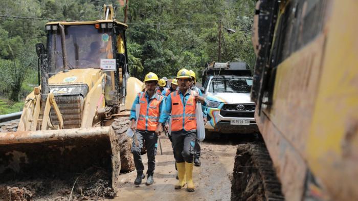 Tampak petugas PLN menyusuri jalur berlumpur menuju titik terdampak di Adian Koting, Tapanuli Utara.