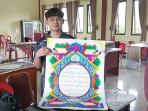 20251110-Apriyansah-dari-Kabupaten-Belitung-menunjukkan-kaligrafi-hasil-karyanya.jpg