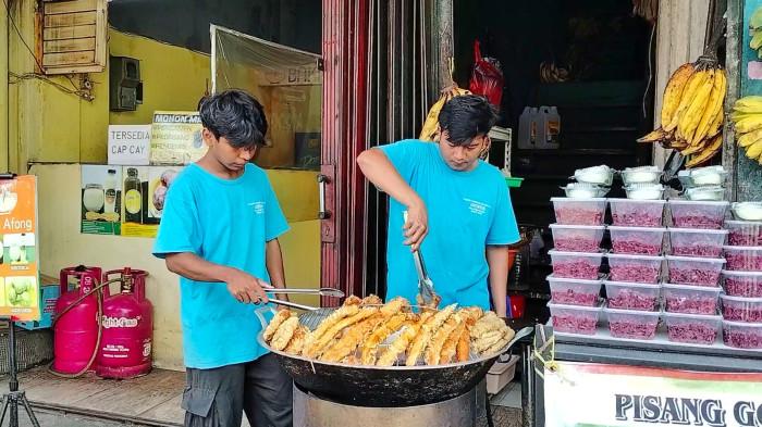 KULINER BOGOR – Pegawai Pisang Goreng Kalimantan Ameng Asli Pontianak tampak menggoreng pisang kipas khas Kalimantan. penggorengan menggunakan wajan besar agar menghasilkan tekstur renyah di luar dan lembut di dalam.