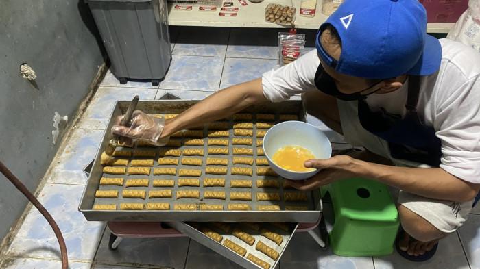KULINER BOGOR - Seorang pengrajin Roti Gambang Sa’arina tengah mengoleskan kuning telur pada adonan sebelum dipanggang.