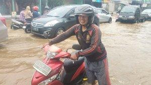 Kurniawan-menuntun-sepeda-motornya-yang-mogok-saat-menerjang-banjir.jpg