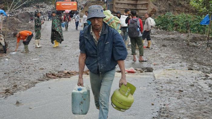 BAWA TABUNG GAS - Seorang warga membawa tabung gas elpiji saat melintas jalan KKA (Bener Meriah- Aceh Utara), Selasa (16/12/2025). Tribungayo.com/Bustami
