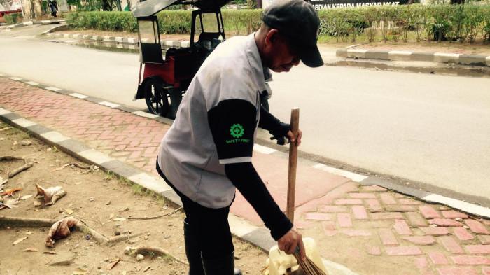 PETUGAS KEBERSIHAN -- Adrian Oyintu saat menyapu halaman Universitas Negeri Gorontalo, Senin (6/4/2026). Adrian merupakan petugas kebersihan UNG.