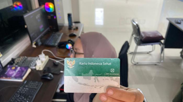 BPJS -- Seorang pekerja kantoran memegang kartu BPJS Kesehatan. Saat ini diketahui iuran BPJS kelas 3 rencana dihapus.