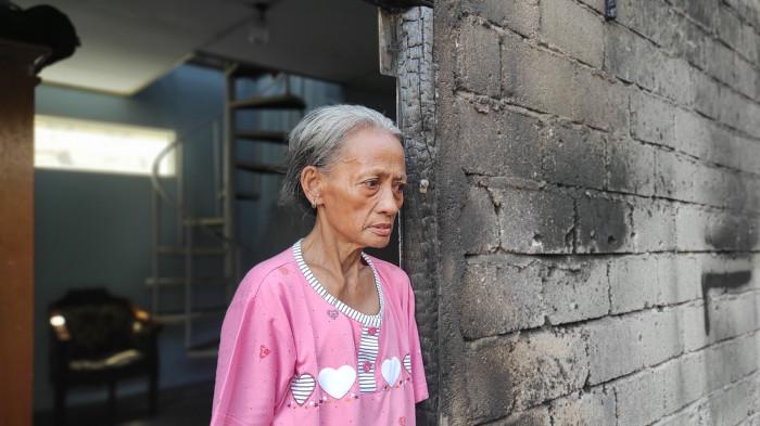 KEBAKARAN RUMAH -- Dona Karim (50) menatap puing-puing rumah kayu miliknya yang ludes terbakar di Kelurahan Moodu, Kota Gorontalo, Selasa (27/1/2025) dini hari. Ia menceritakan detik-detik kebakaran yang menghanguskan satu-satunya tempat tinggal miliknya.