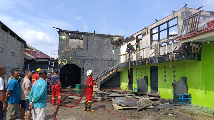 KEBAKARAN -- Seorang pemadam kebakaran (damkar) menyemprotkan air ke arah gedung Cafe Tiara yang terbakar. Meski api sudah mati, namun air ini digunakan agar tak muncul bibit api.