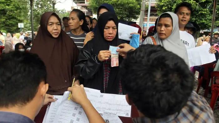 PENCAIRAN BANTUAN SOSIAL - Petugas menyalurkan dana bantuan sosial kepada warga di Lapangan Sejati, Medan, Senin (24/11/2025). Masyarakat dapat mengecek status penerima PKH dan BPNT Tahap 2 Tahun 2026 melalui situs Kemensos menggunakan NIK KTP, sementara pencairan bantuan dijadwalkan berlangsung pada Mei 2026.