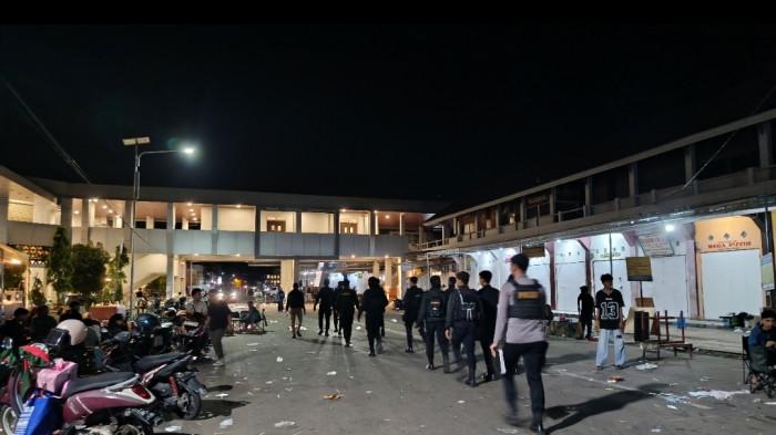 AMANKAN KERICUHAN — Belasan polisi mengamankan Pasar Sentral pada Minggu (7/12/2025) dini hari Wita. Insiden penikaman memicu kepanikan warga.
