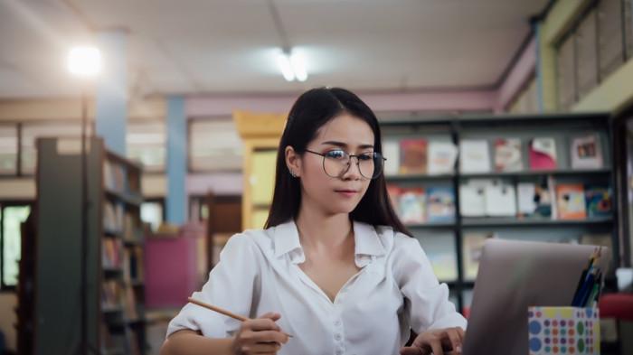 Potret wanita belajar di perpustakaan.