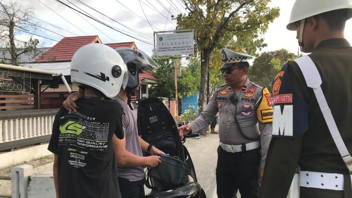 OPERASI ZEBRA -- Satlantas Polresta Gorontalo Kota melaksanakan Operasi Zebra Otanaha di Jalan Arif Rahman Hakim, Sabtu (29/11/2025). Seorang pemuda mengenakan kaus polisi diberhentikan petugas. (Sumber foto: TribunGorontalo.com/Jefri Potabuga)