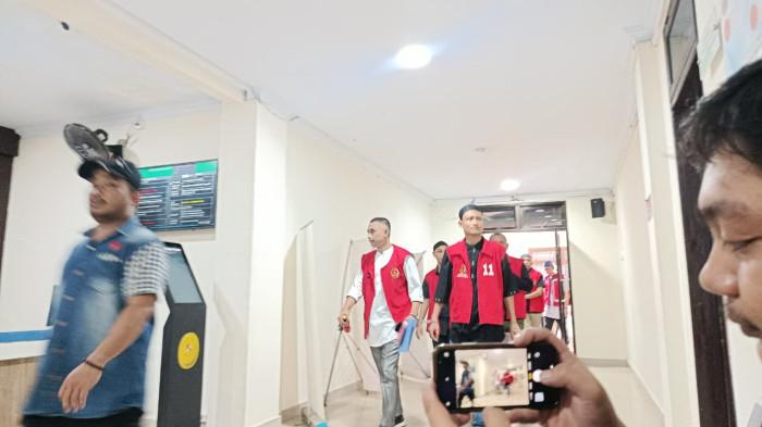 KASUS PELECEHAN -- Sosok Muhammad Amin Ramadhan (mengenakan kemeja putih dan rompi merah) tersangka kasus dugaan pelecehan seksual tiba di Pengadilan Negeri Gorontalo. Amin akan menjalani sidang perdana pada Selasa (28/4/2206). (Sumber foto: TribunGorontalo.com/Jefri Potabuga)