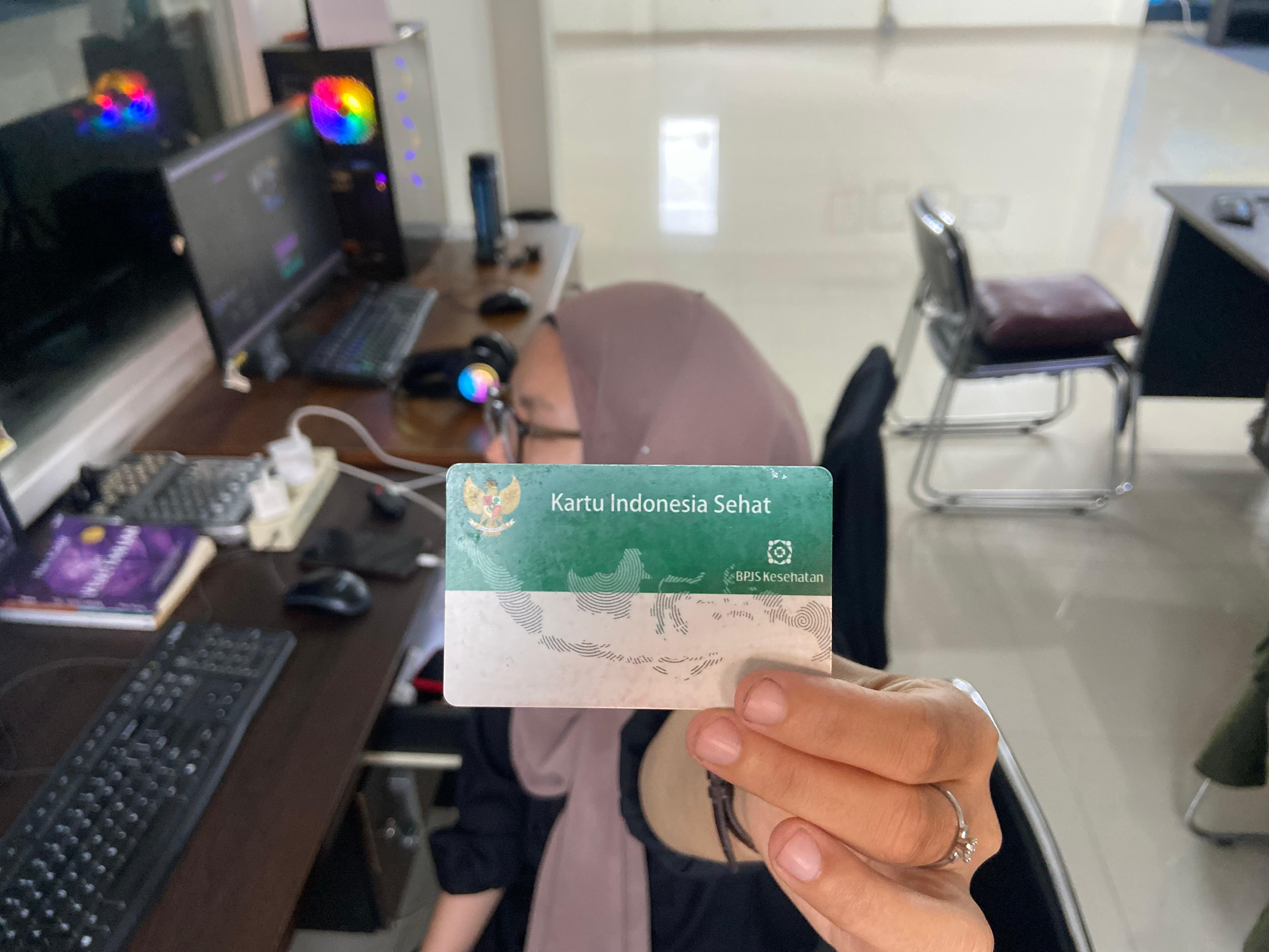BPJS-Seorang-pekerja-kantoran-memegang-kartu-BPJS-Kesehatan.jpg