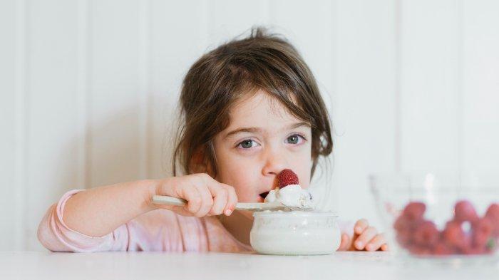 Ilustrasi anak makan yogurt, berikut manfaat yogurt untuk mendukung tumbuh kembang anak