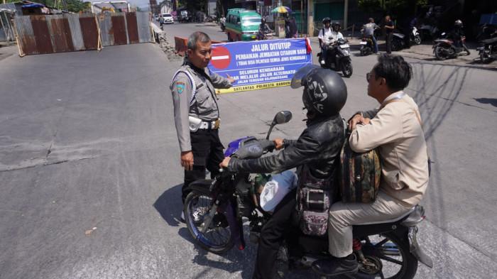 Petugas kepolisian memberhentikan pengendara sepeda motor dari arah Dayeuhkolot yang akan melintas ke Jembatan Citarum Lama yang hanya diberlakukan satu arah untuk kendaraan yang dari arah Baleendah, saat proses perbaikan Jembatan Citarum Baru, di Kecamatan Dayeuhkolot, Kabupaten Bandung, Jawa Barat, Senin (28/7/2025).