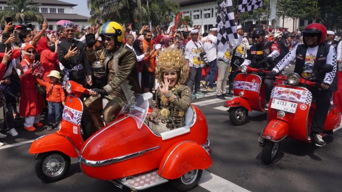 Wakil Gubernur Jawa Barat, Erwan Setiawan bersama istri Samantha Dewi mengenakan busana tradisional naik Vespa mengikuti Kirab Merah Putih seusai upacara bendera peringatan Hari Ulang Tahun (HUT) ke-80 Kemerdekaan Republik Indonesia tingkat Provinsi Jawa Barat, di Jalan Diponegoro, Kota Bandung, Jawa Barat, Minggu (17/8/2025).