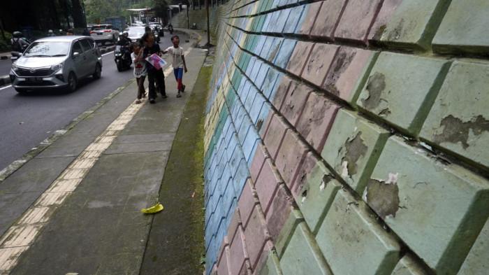 Pengguna jalan melintas di samping mural yang sudah kusam di Jalan Siliwangi (Babakan Siliwangi), Kota Bandung, Jawa Barat, Jumat (22/8/2025).