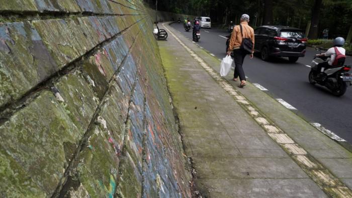Pengguna jalan melintas di samping mural yang sudah kusam di Jalan Siliwangi (Babakan Siliwangi), Kota Bandung, Jawa Barat, Jumat (22/8/2025).