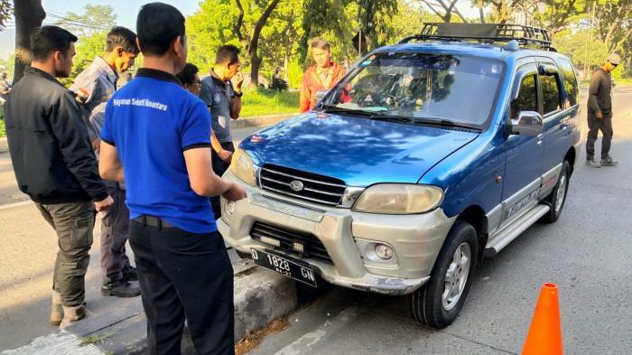 Sejumlah warga dan pegawai Kecamatan Panyileukan menyaksikan mobil Daihatsu Taruna yang tersangkut di atas marka Jalan Soekarno Hatta, Kota Bandung, Jawa Barat, Rabu (27/8/2025).