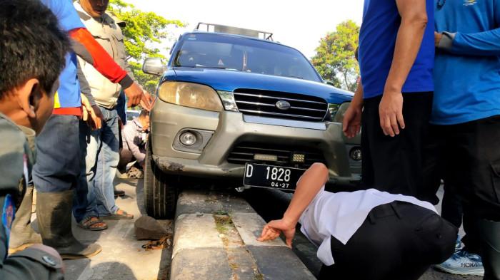 Sejumlah warga dan pegawai Kecamatan Panyileukan menyaksikan mobil Daihatsu Taruna yang tersangkut di atas marka Jalan Soekarno Hatta, Kota Bandung, Jawa Barat, Rabu (27/8/2025).