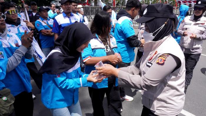 Sejumlah Polwan membagikan air minum kepada massa buruh dari Serikat Pekerja Nasional (SPN) Jawa Barat yang sedang menggelar aksi unjuk rasa di depan Gedung Sate, Jalan Diponegoro, Kota Bandung, Jawa Barat, Kamis (28/8/2025).