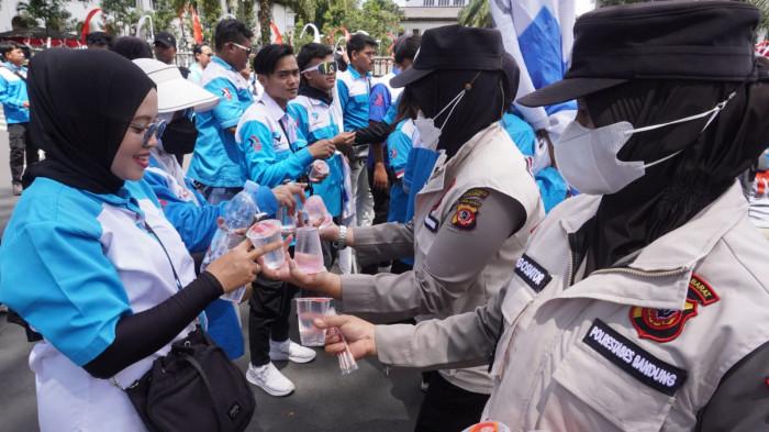 Sejumlah Polwan membagikan air minum kepada massa buruh dari Serikat Pekerja Nasional (SPN) Jawa Barat yang sedang menggelar aksi unjuk rasa di depan Gedung Sate, Jalan Diponegoro, Kota Bandung, Jawa Barat, Kamis (28/8/2025).