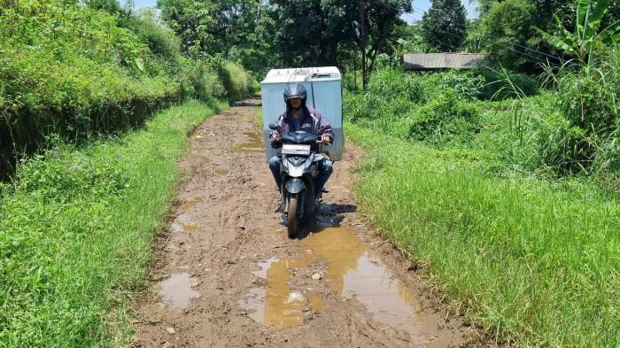 Pengguna jalan melintas di jalan rusak dengan permukaan berlumpur dan digenangi air di Kapung Parunghalang, Kelurahan Andir, Kecamatan Baleendah, Kabupaten Bandung, Provinsi Jawa Barat, Sabtu (13/9/2025).