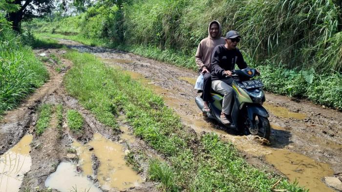Pengguna jalan melintas di jalan rusak dengan permukaan berlumpur dan digenangi air di Kapung Parunghalang, Kelurahan Andir, Kecamatan Baleendah, Kabupaten Bandung, Provinsi Jawa Barat, Sabtu (13/9/2025).