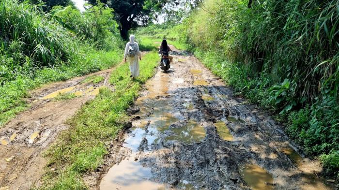 Pengguna jalan melintas di jalan rusak dengan permukaan berlumpur dan digenangi air di Kapung Parunghalang, Kelurahan Andir, Kecamatan Baleendah, Kabupaten Bandung, Provinsi Jawa Barat, Sabtu (13/9/2025).