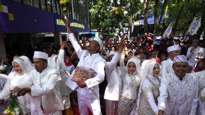 Pasang pengantin yang sudah melangsungkan akad nikah melempar bunga kepada kerumunan warga dalam gelaran Nikah Gratis di Mal Pelayanan Publik (MPP) Kota Bandung,  Jalan Sukabumi, Kota Bandung, Jawa Barat, Jumat (26/9/2025).