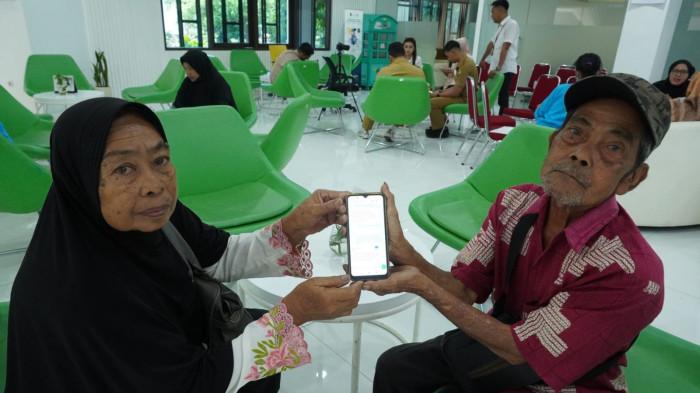 Dua orang tua suami istri memperlihatkan ponselnya yang berisi tindakan penipuan lewat WhatsApp (WA) yang menimpa keduanya saat akan melakukan pengaduan di Bale Pananggeuhan, Pelayanan dan Pengaduan Satu Pintu Setda Provinsi Jawa Barat, kompleks Gedung Sate, Kota Bandung, Jawa Barat, Senin (6/10/2025).