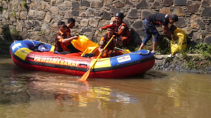 Sejumlah anggota Pemuda Pancasila (PP) Kota Bandung naik perahu karet mencabut rumput liar di aliran Sungai Cikapundung, Kota Bandung, Jawa Barat, Selasa (7/10/2025).