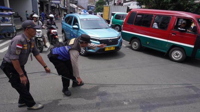 Petugas Bhabinkamtibmas dan Linmas Kelurahan Braga serta warga melakukan upaya pengamanan kabel fiber optik/internet yang menjuntai ke badan jalan, di Persimpangan Jalan Banceuy - Suniaraja, Kota Bandung, Jawa Barat, Rabu (29/10/2025).
