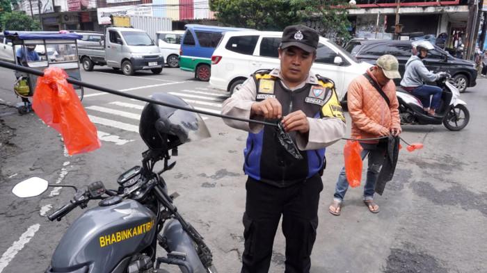 Petugas Bhabinkamtibmas dan Linmas Kelurahan Braga serta warga melakukan upaya pengamanan kabel fiber optik/internet yang menjuntai ke badan jalan, di Persimpangan Jalan Banceuy - Suniaraja, Kota Bandung, Jawa Barat, Rabu (29/10/2025).