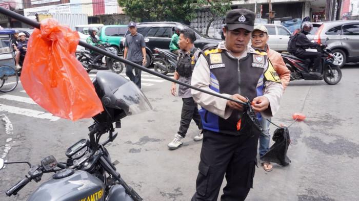 Petugas Bhabinkamtibmas dan Linmas Kelurahan Braga serta warga melakukan upaya pengamanan kabel fiber optik/internet yang menjuntai ke badan jalan, di Persimpangan Jalan Banceuy - Suniaraja, Kota Bandung, Jawa Barat, Rabu (29/10/2025).