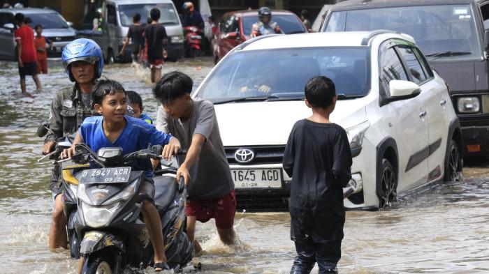 Pengguna jalan melintasi banjir yang merendam Jalan Raya Dayeuhkolot, di Kecamatan Dayeuhkolot, Kabupaten Bandung, Jawa Barat, Senin (3/11/2025).