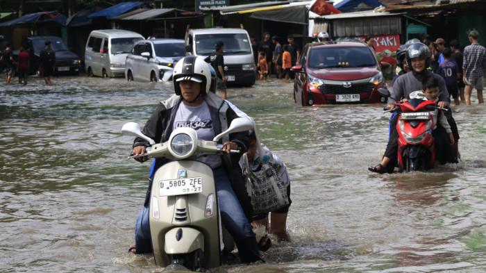 Pengguna jalan melintasi banjir yang merendam Jalan Raya Dayeuhkolot, di Kecamatan Dayeuhkolot, Kabupaten Bandung, Jawa Barat, Senin (3/11/2025).