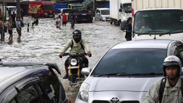 Pengguna jalan melintasi banjir yang merendam Jalan Raya Dayeuhkolot, di Kecamatan Dayeuhkolot, Kabupaten Bandung, Jawa Barat, Senin (3/11/2025).